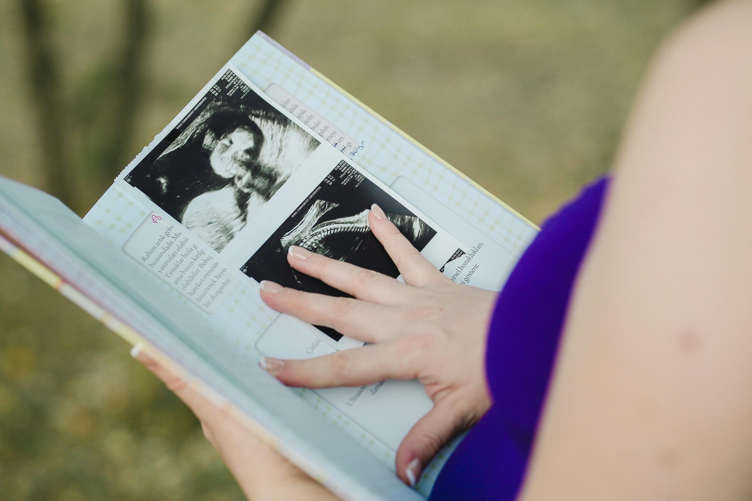 A mother writing in a baby memory journal with soft natural light in the background